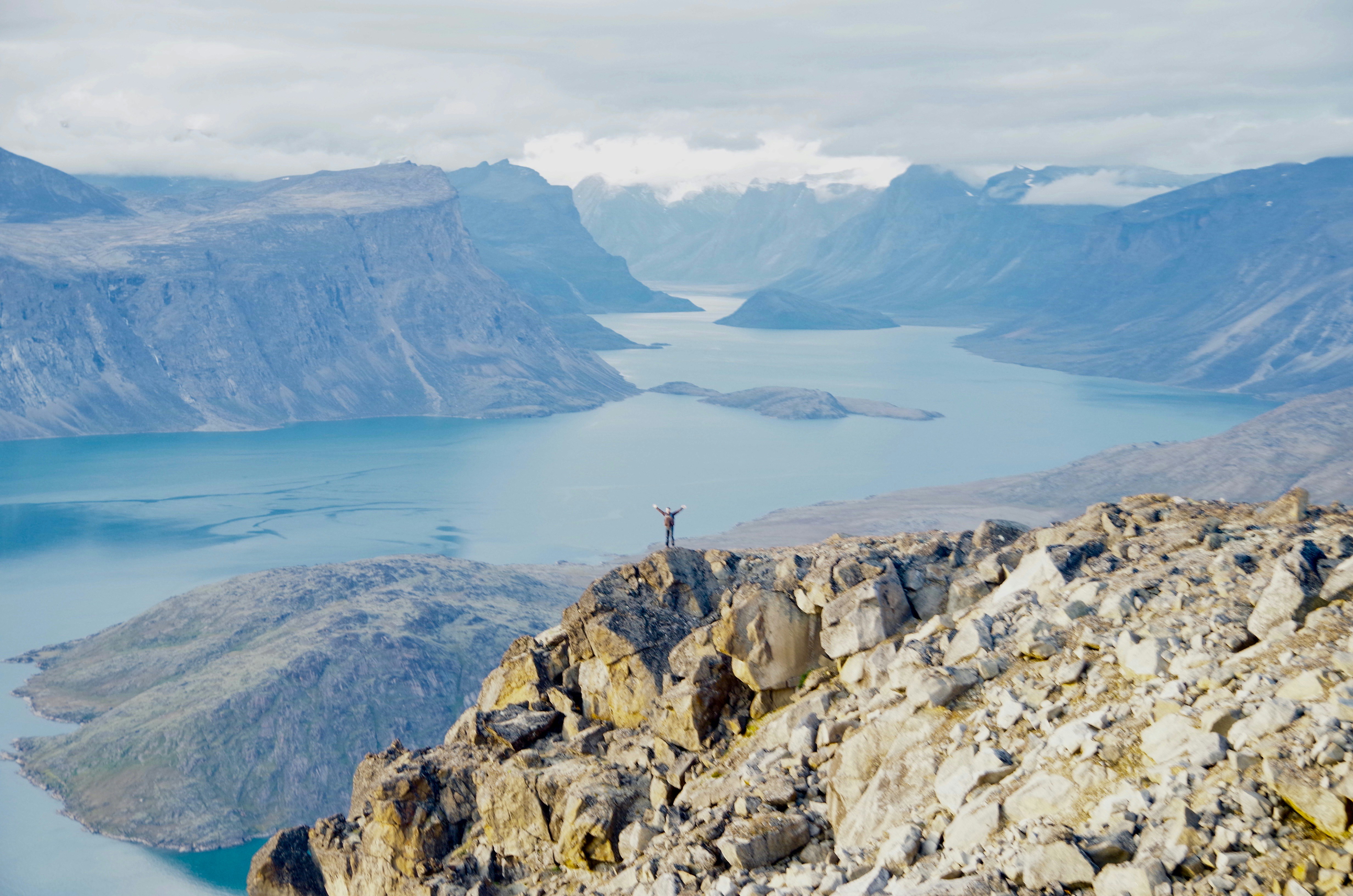 a man standing on top of a mountain next to a lake