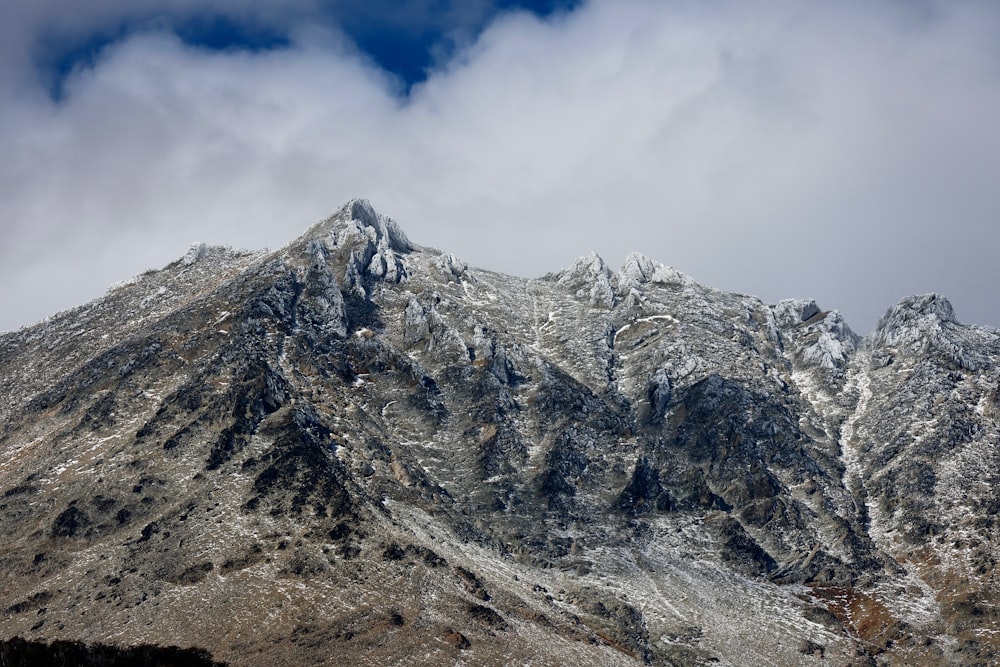 a mountain covered in snow under a cloudy sky