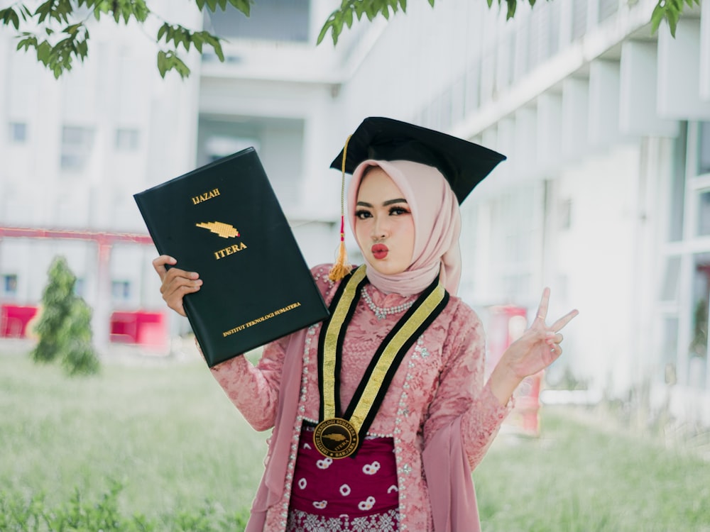 a woman in a graduation gown holding a book