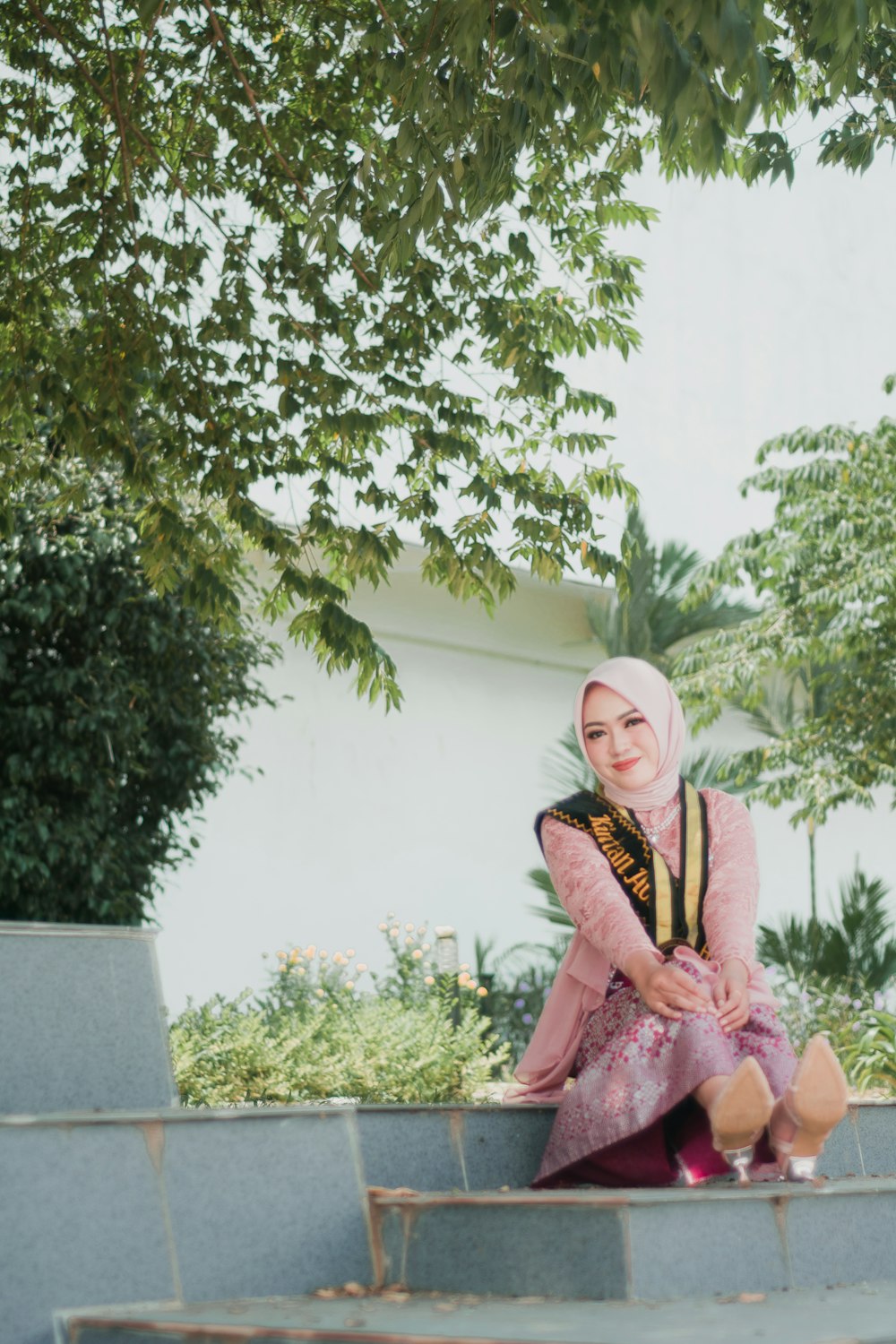 a woman in a pink dress sitting on some steps