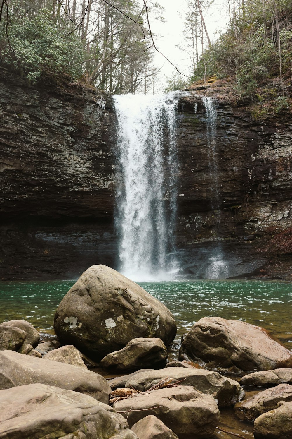 a waterfall with a large rock in the foreground