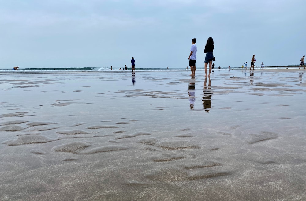 a group of people standing on top of a sandy beach