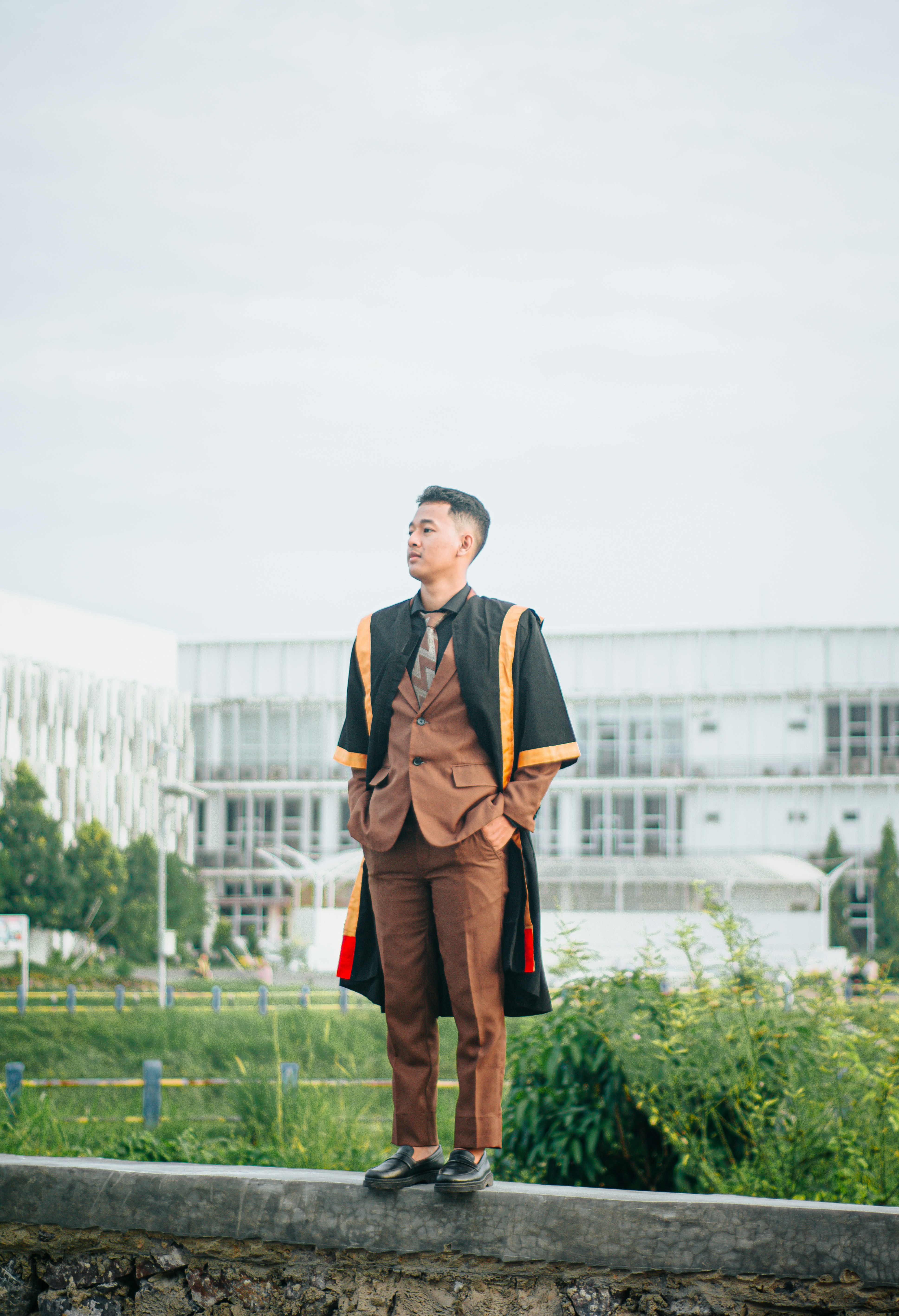 A man standing on a ledge in front of a building photo – Free Man Image ...