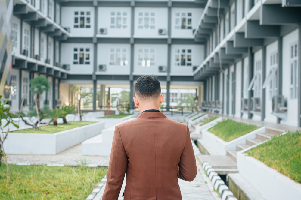 a man in a suit is walking towards a building