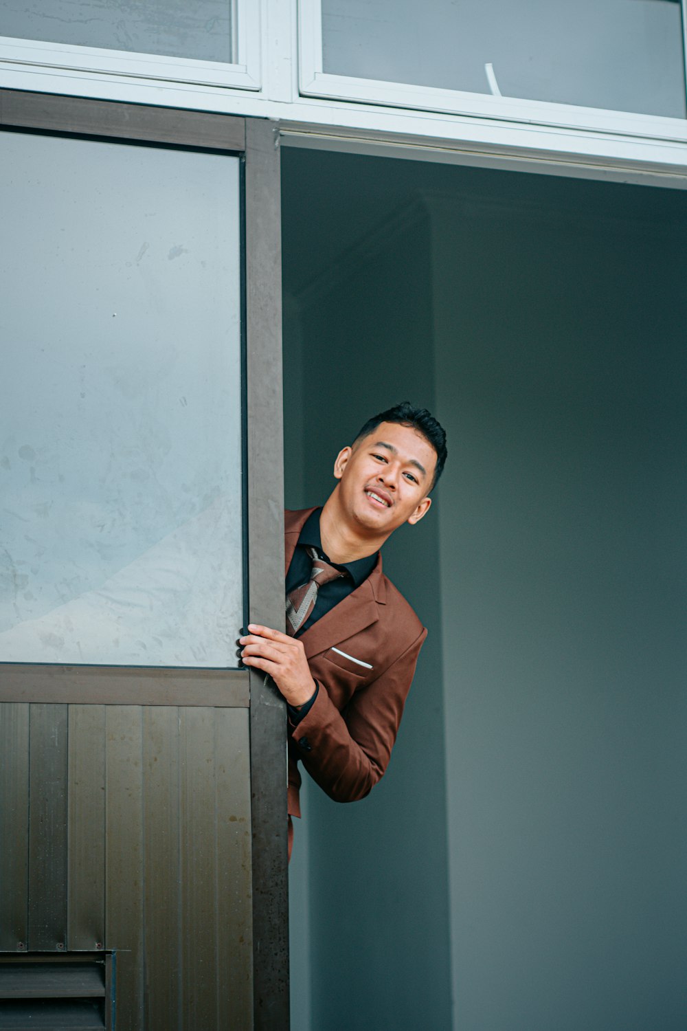 Ein Mann in einem braunen Anzug lehnt an einer Tür