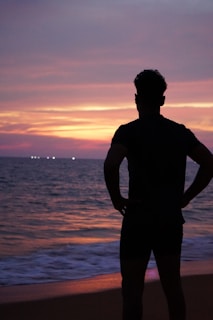 a man standing on top of a beach next to the ocean
