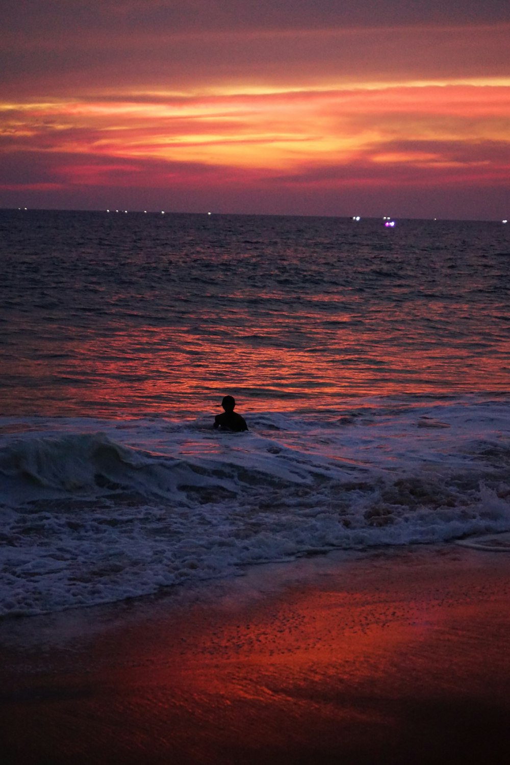 a person swimming in the ocean at sunset