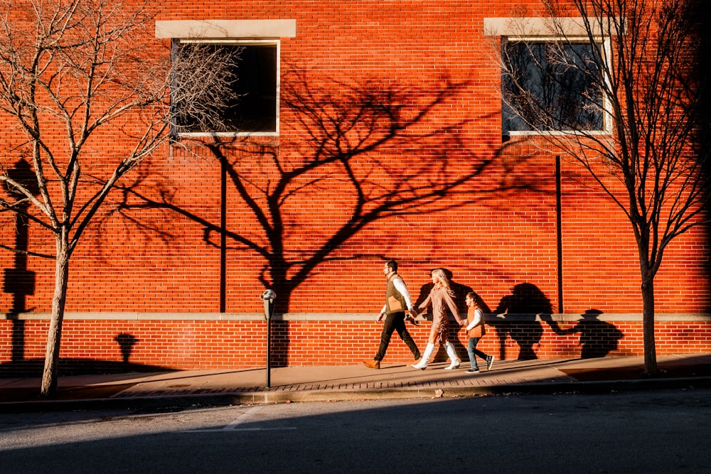 a group of people walking down a street next to a red brick building
