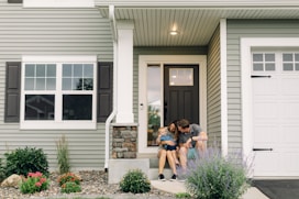 a couple of people that are sitting in front of a house