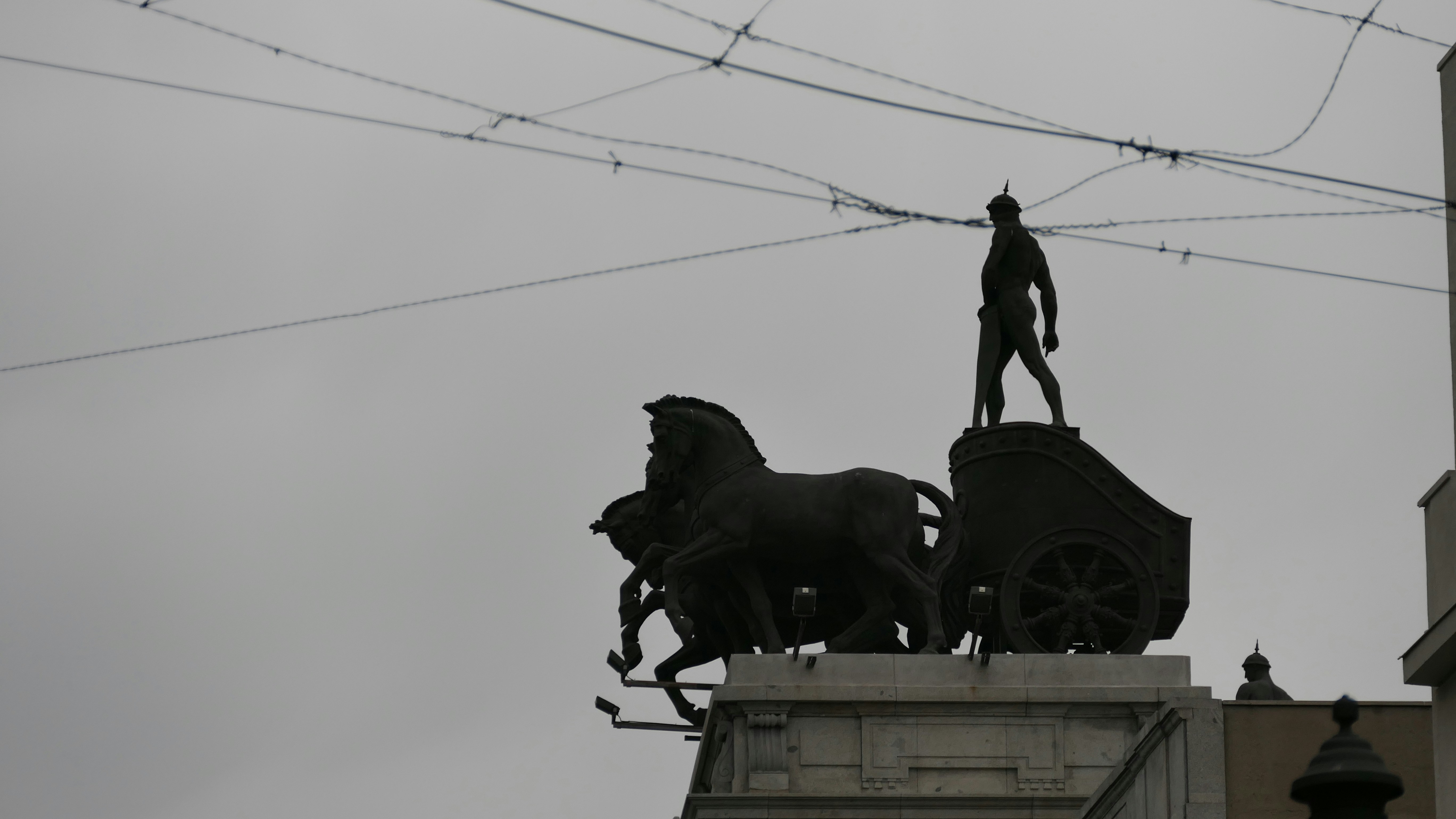 una statua di un uomo in piedi in cima a una carrozza trainata da cavalli
