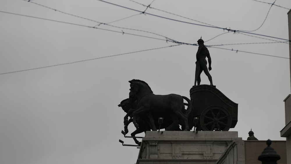 a statue of a man standing on top of a horse drawn carriage