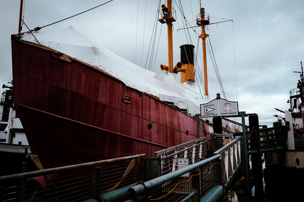 a large red boat sitting on top of a pier