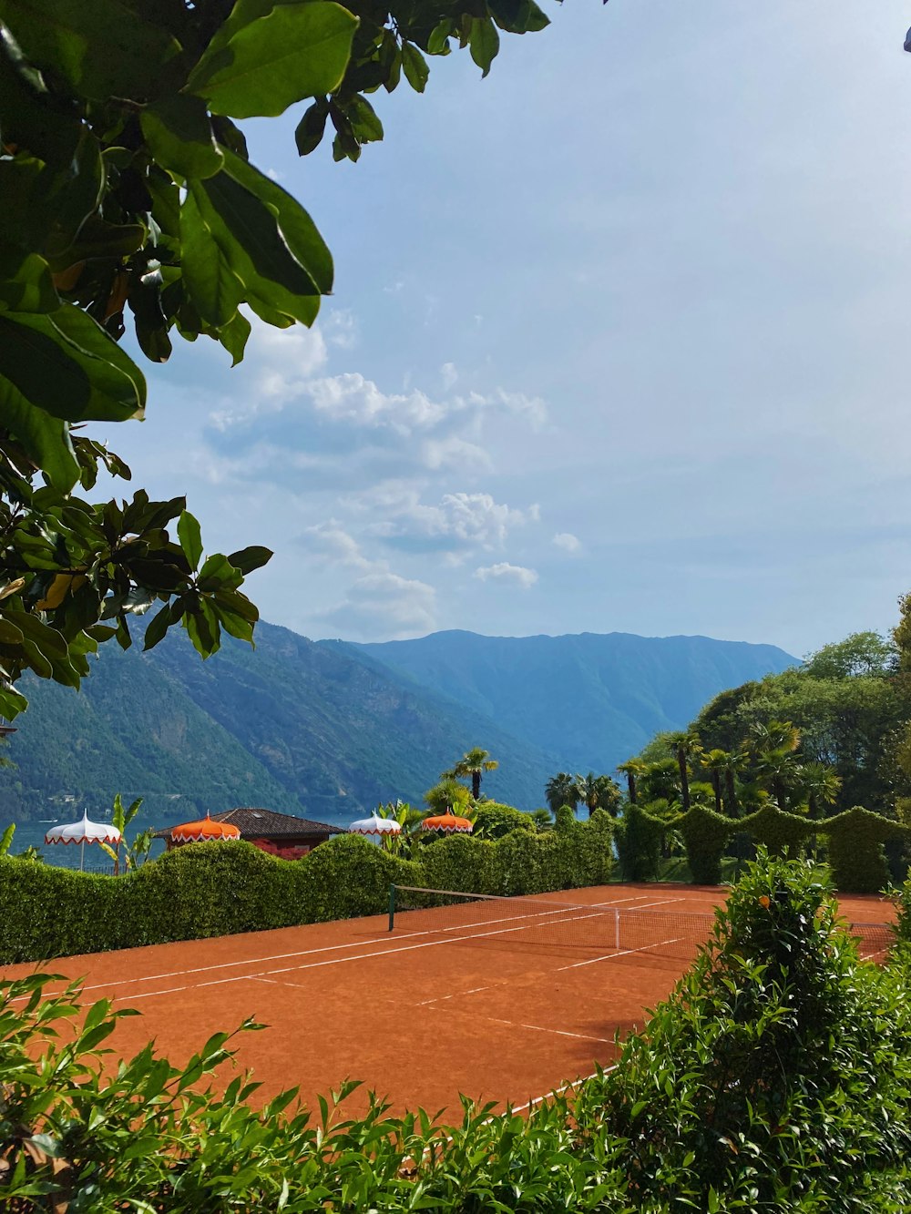 a tennis court surrounded by greenery and mountains
