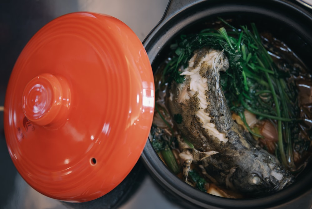 a pot filled with food next to a red lid