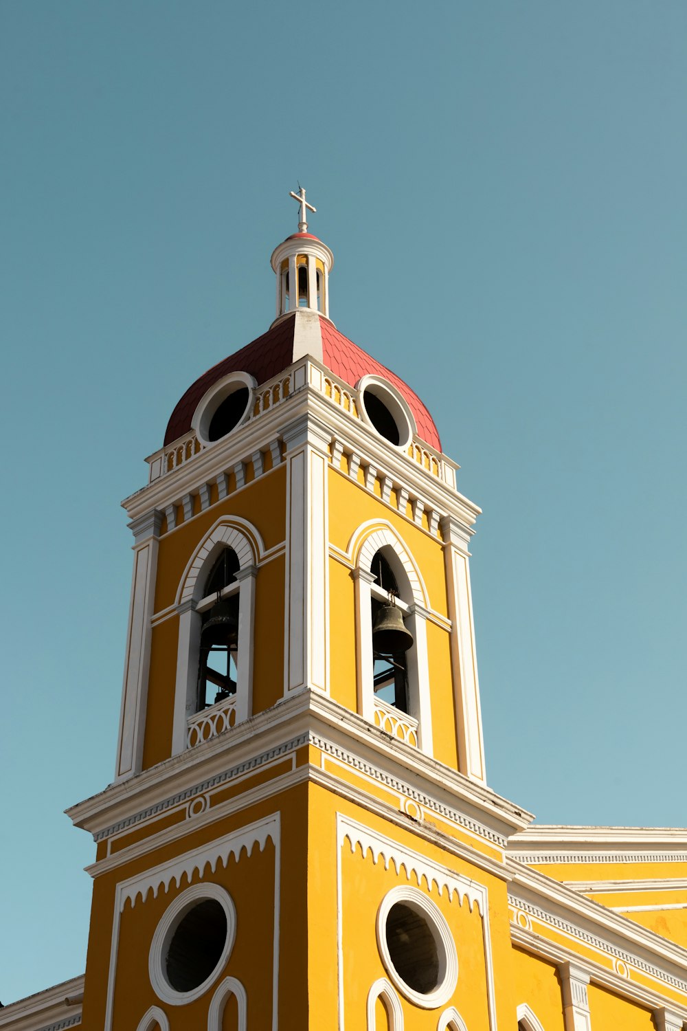 a tall yellow building with a cross on top