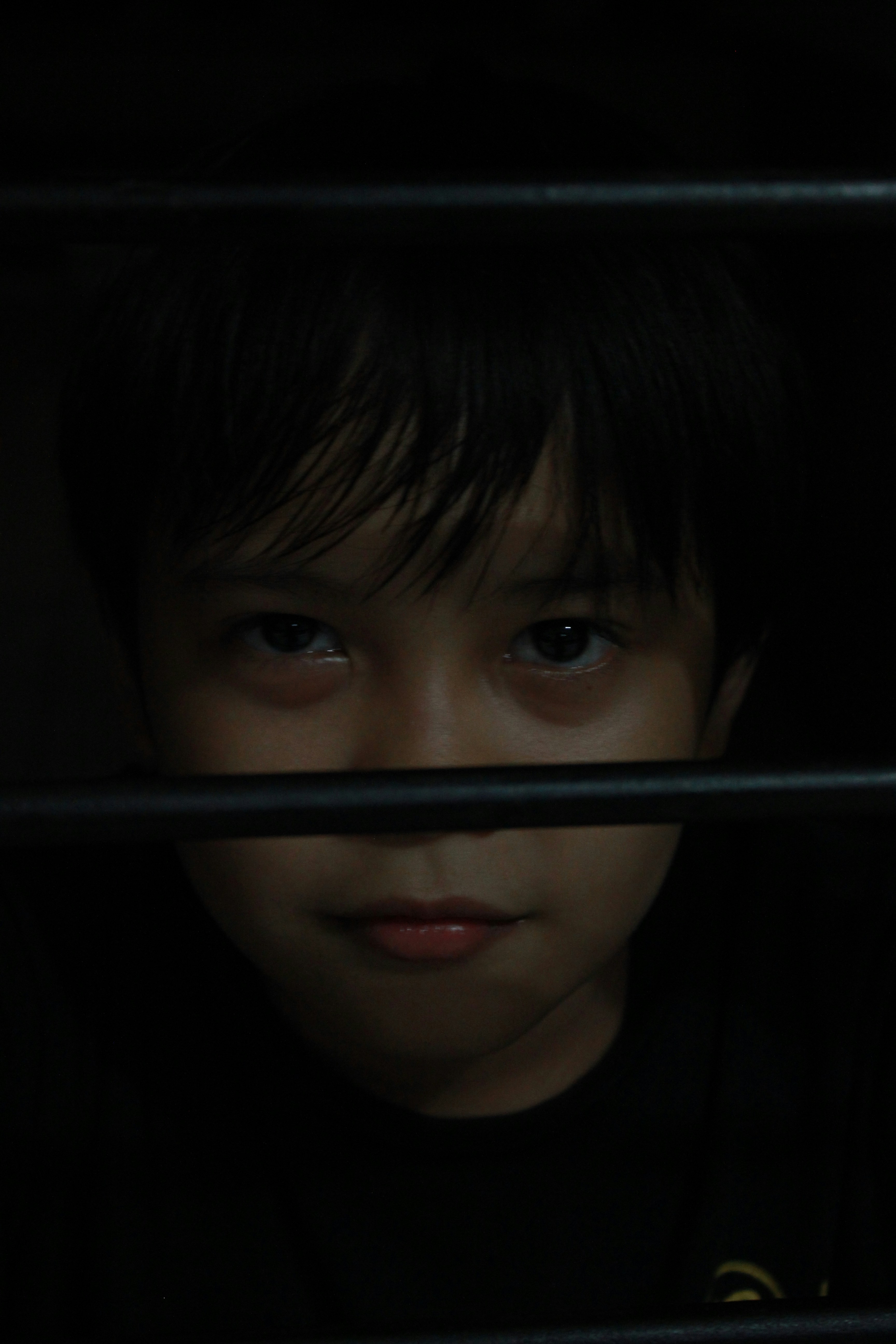 The Dark Side of Child Stardom: 6 Former Kid Actors Who Walked Away – a young boy looking out of a window in the dark