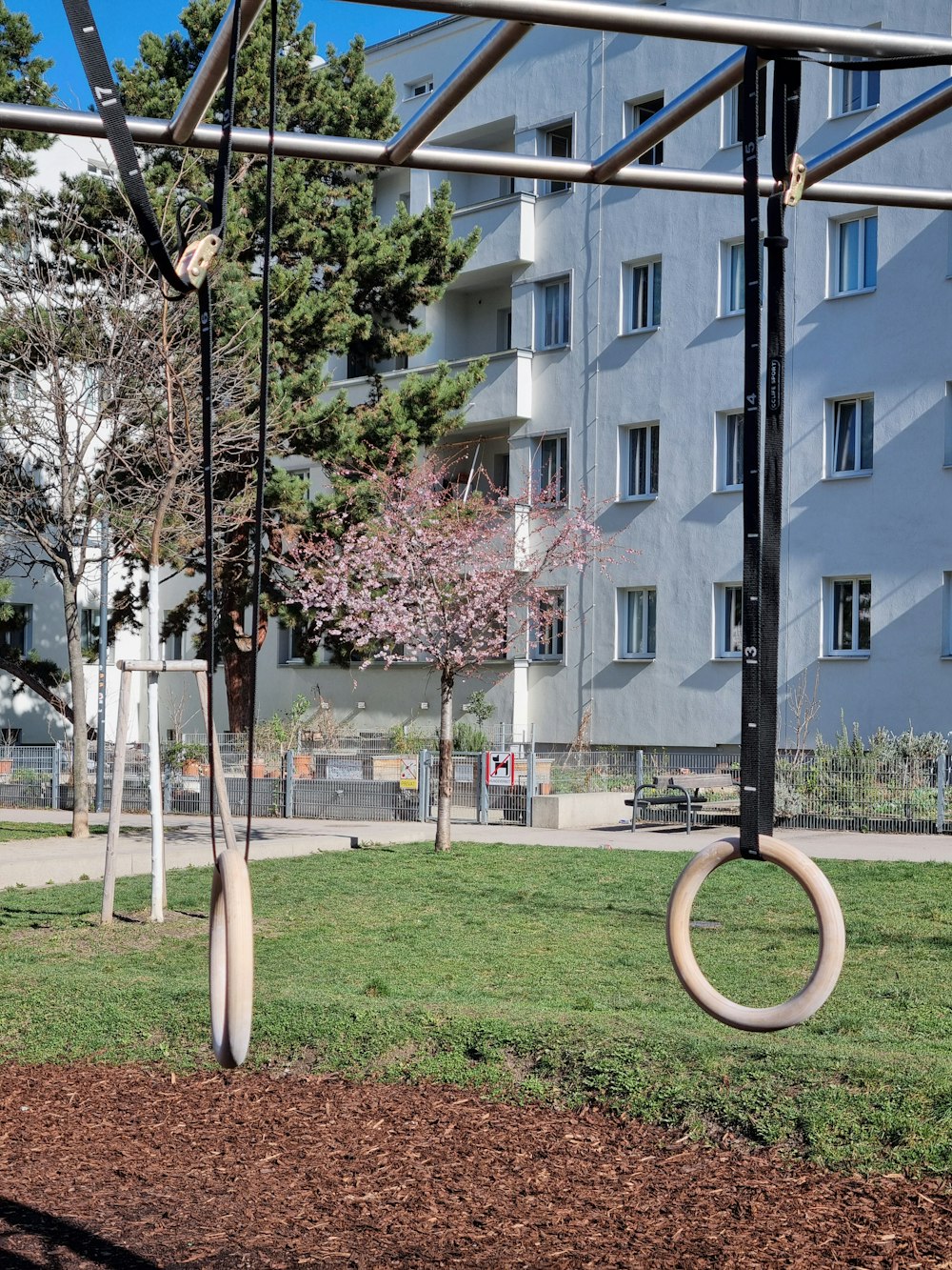 a playground with a swing and a large building in the background