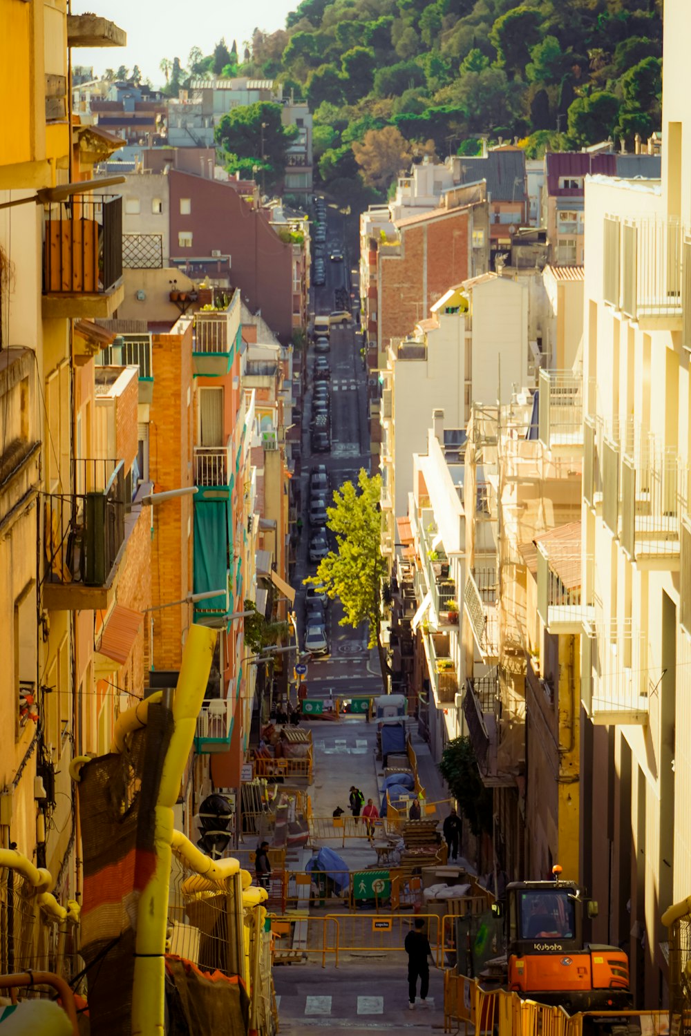 a narrow city street with a hill in the background