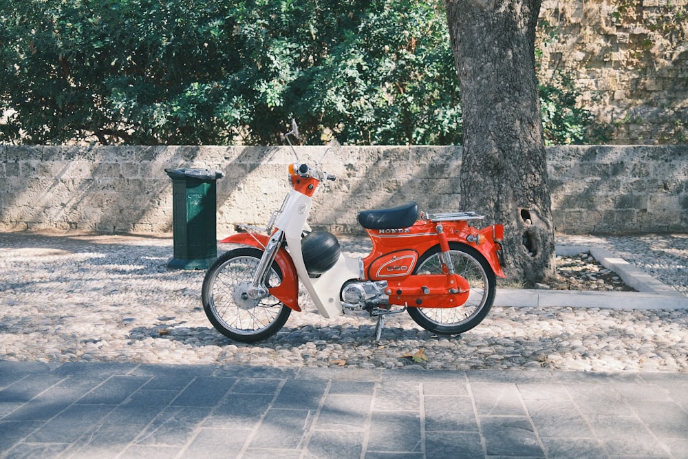 a red and white motorcycle parked next to a tree