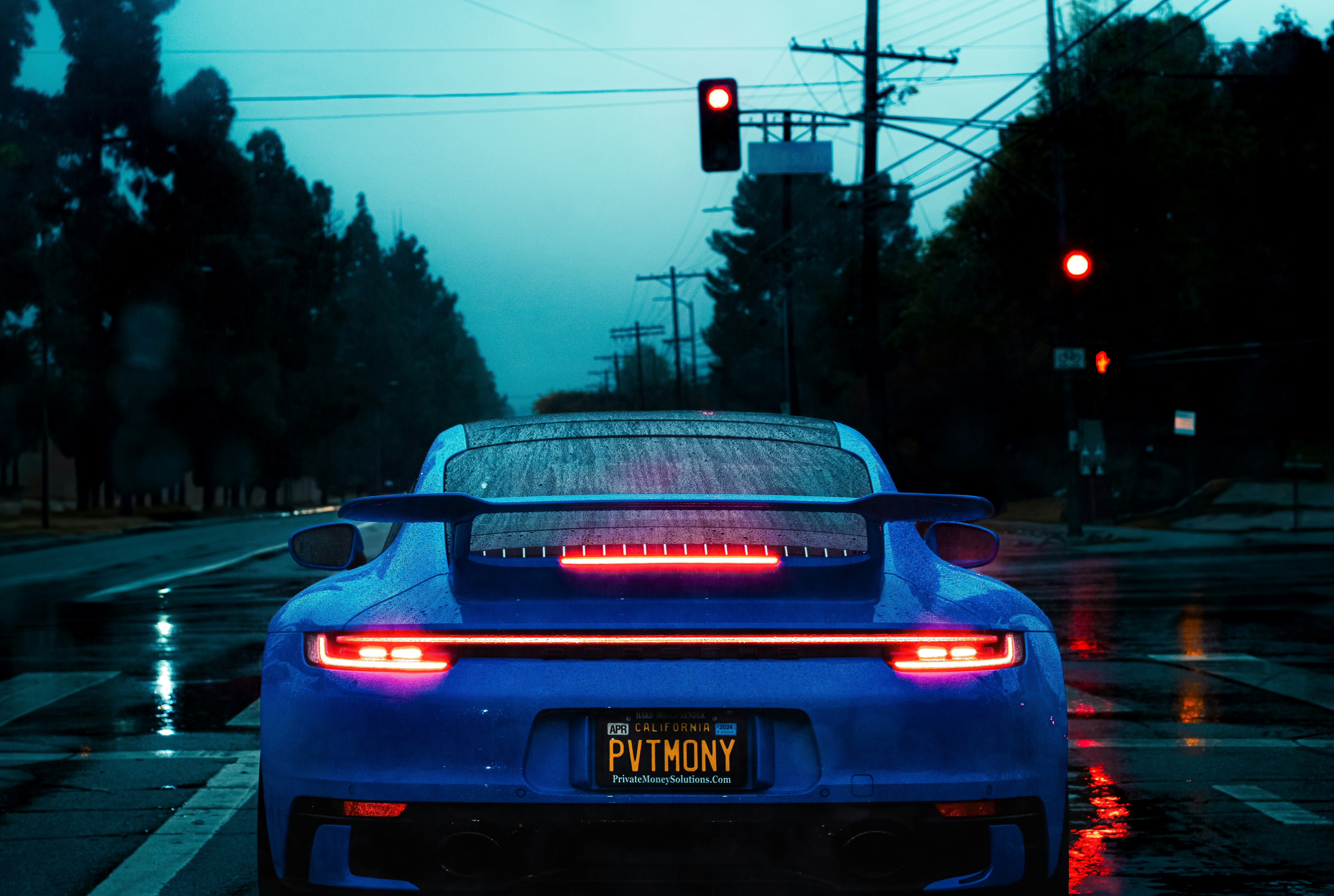 a blue sports car stopped at a red traffic light