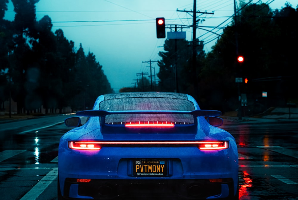 a blue sports car stopped at a red traffic light