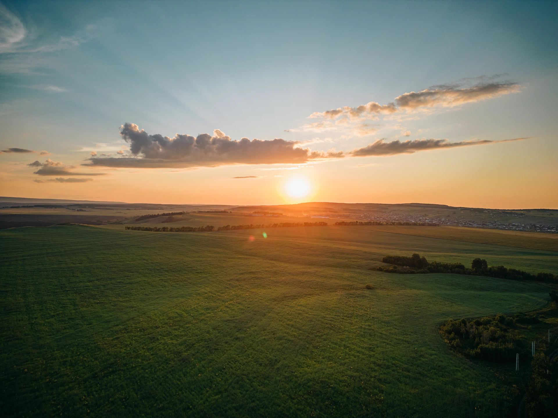 the sun is setting over a green field