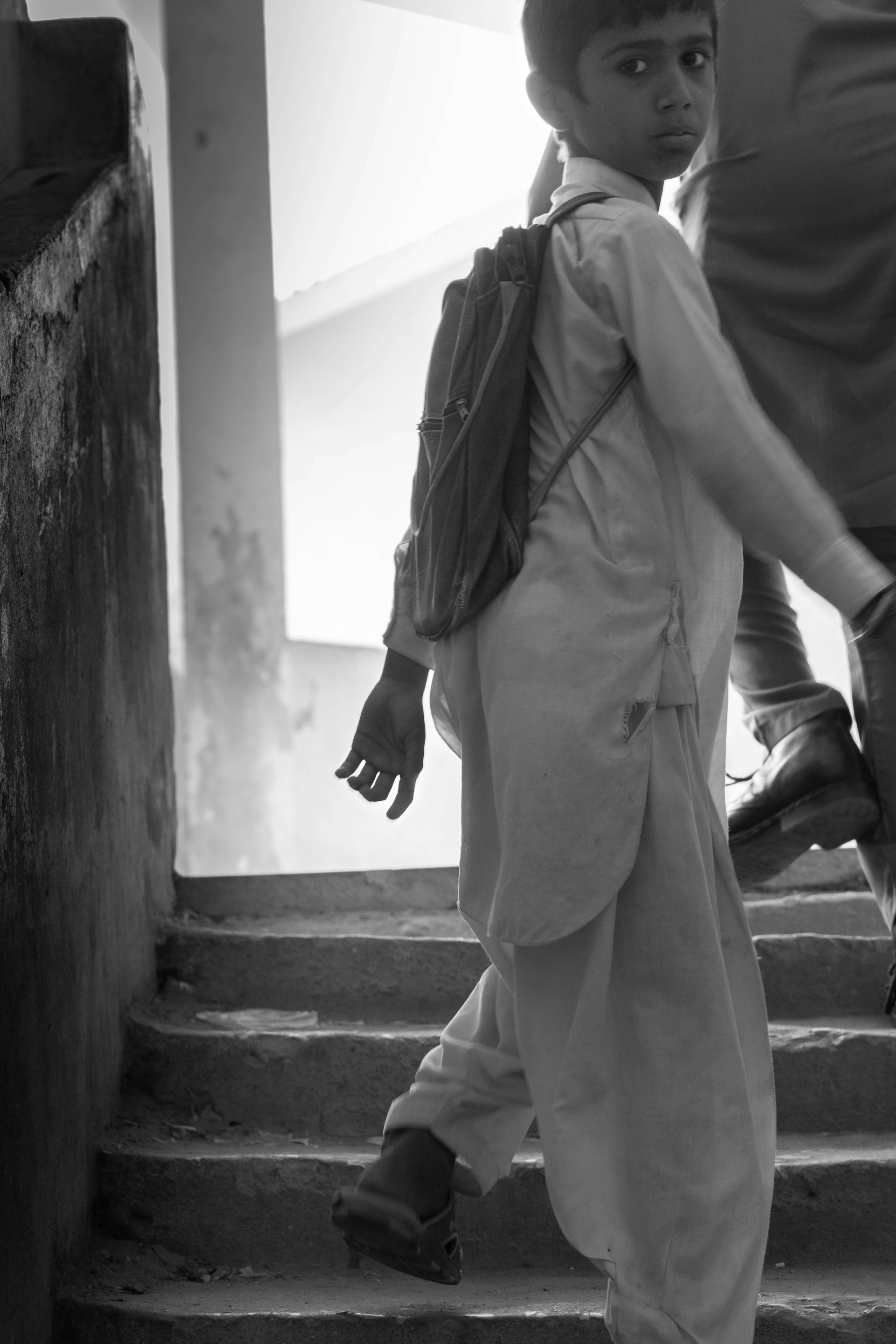 a little boy walking up some steps with a backpack