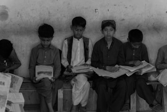 a group of children sitting on a bench reading books