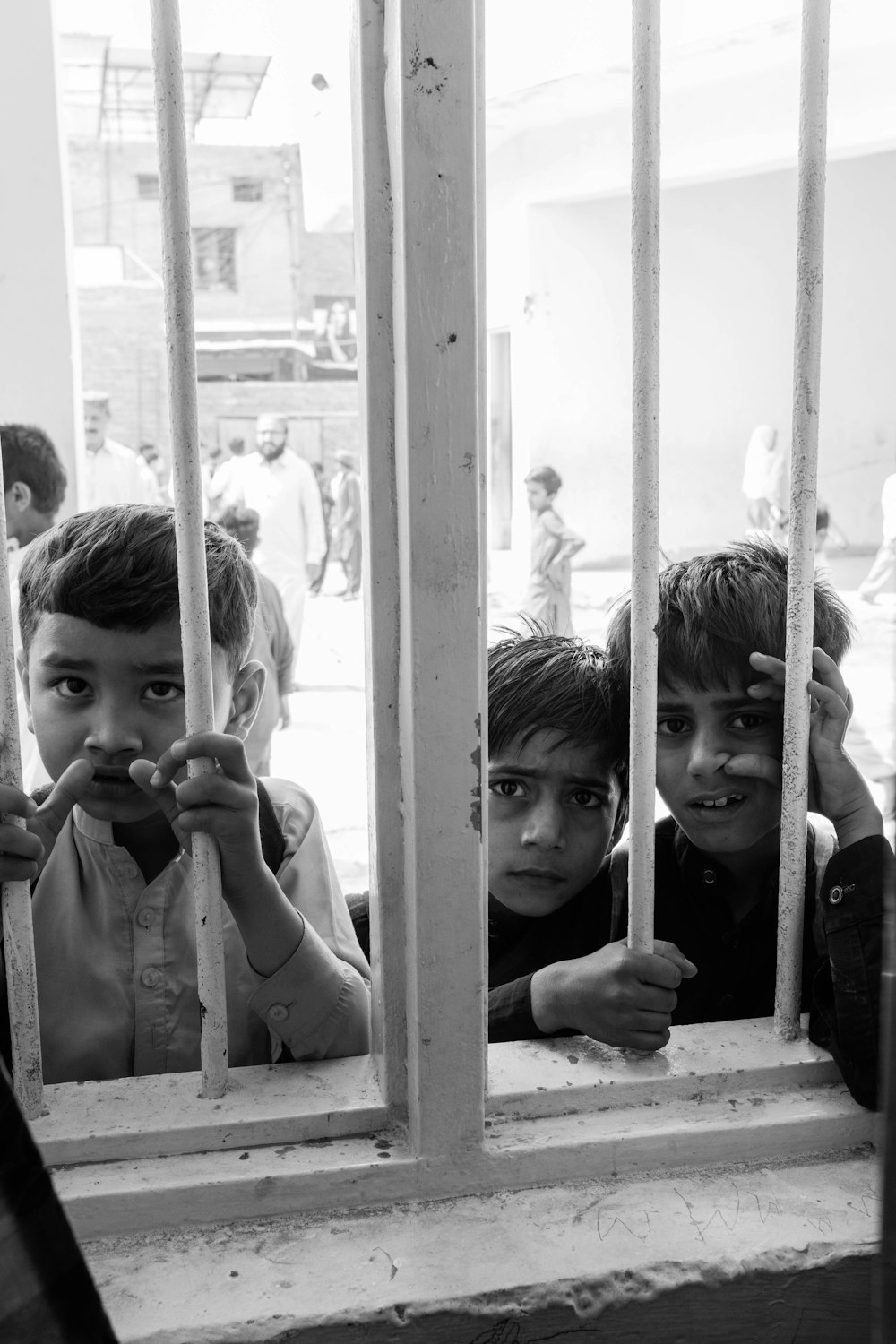 a group of young boys standing behind bars of a jail cell