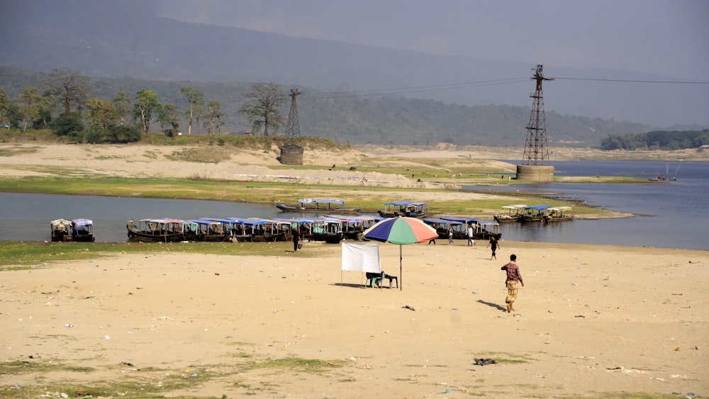 a man standing on top of a sandy beach next to a body of water