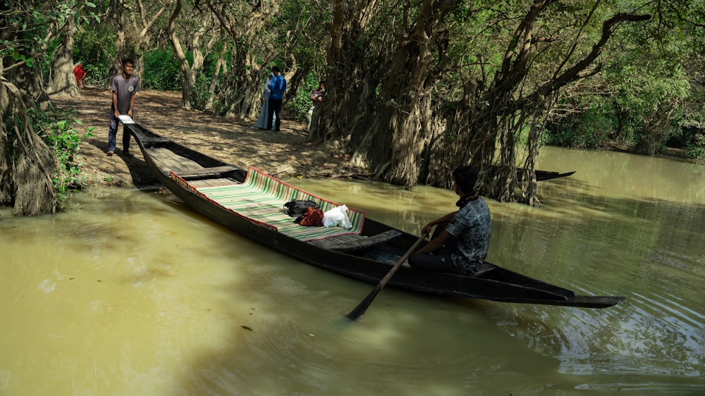 a man is rowing a boat down a muddy river