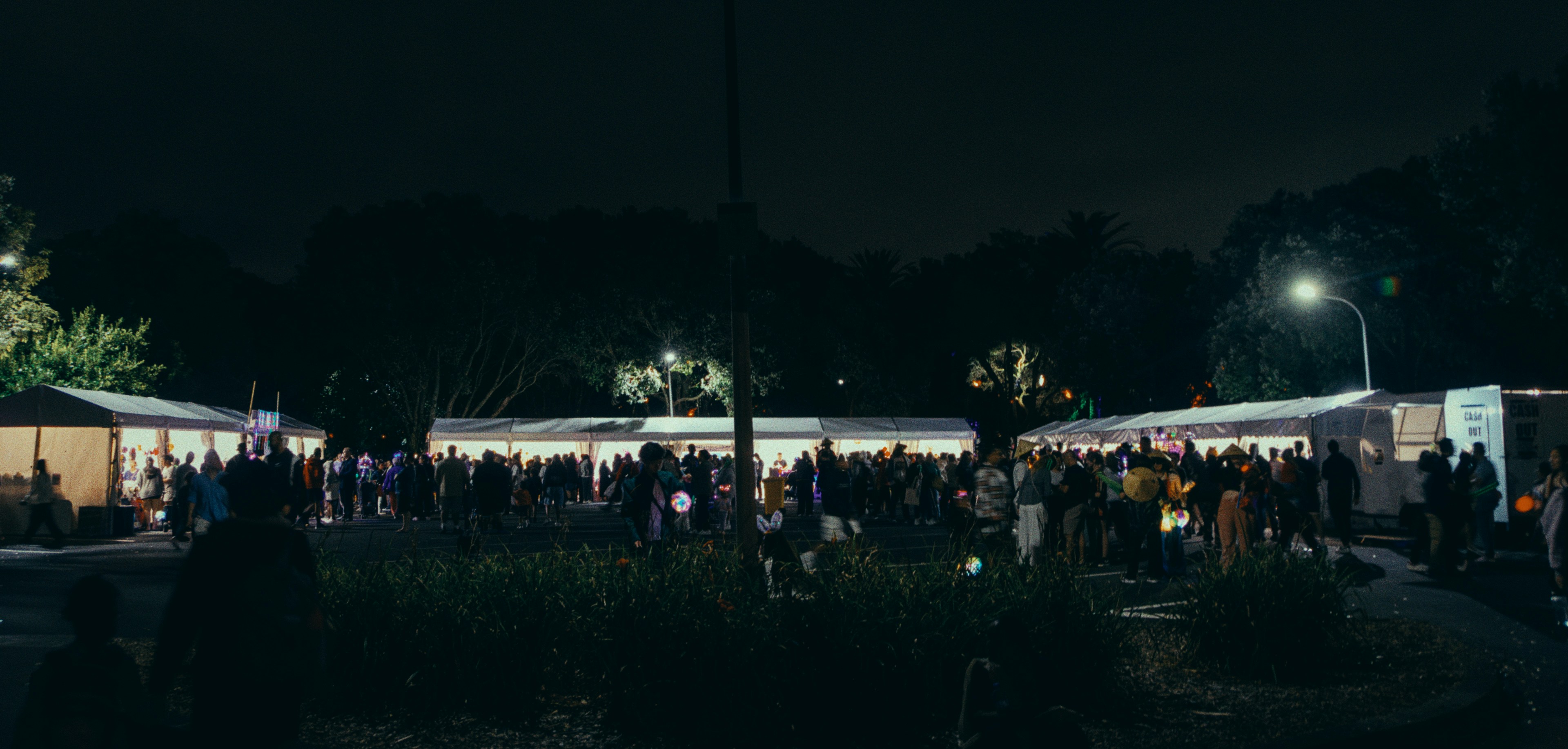 a crowd of people standing around tents at night