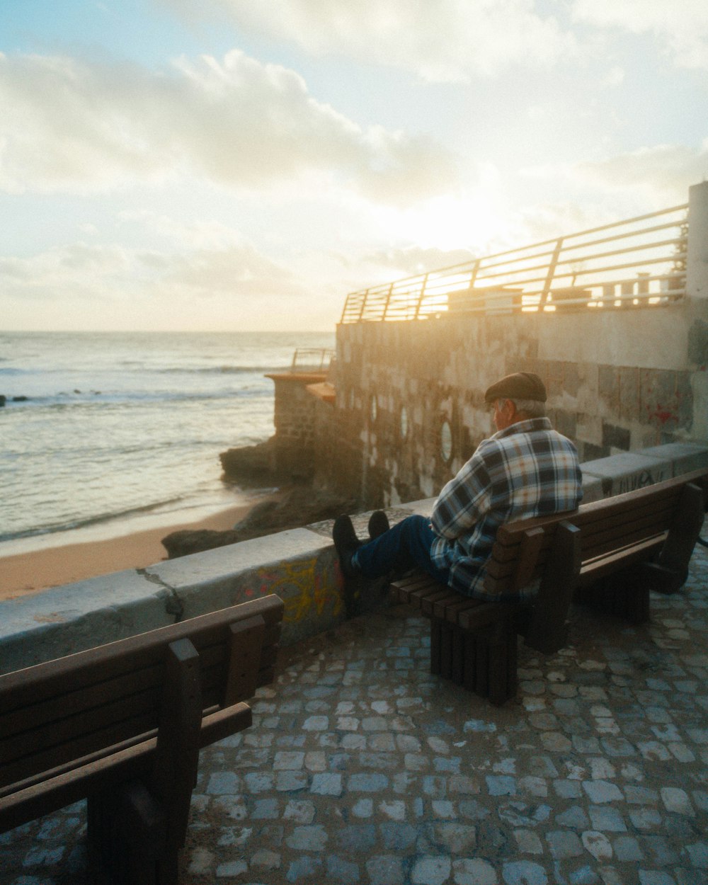 a man sitting on a bench next to the ocean