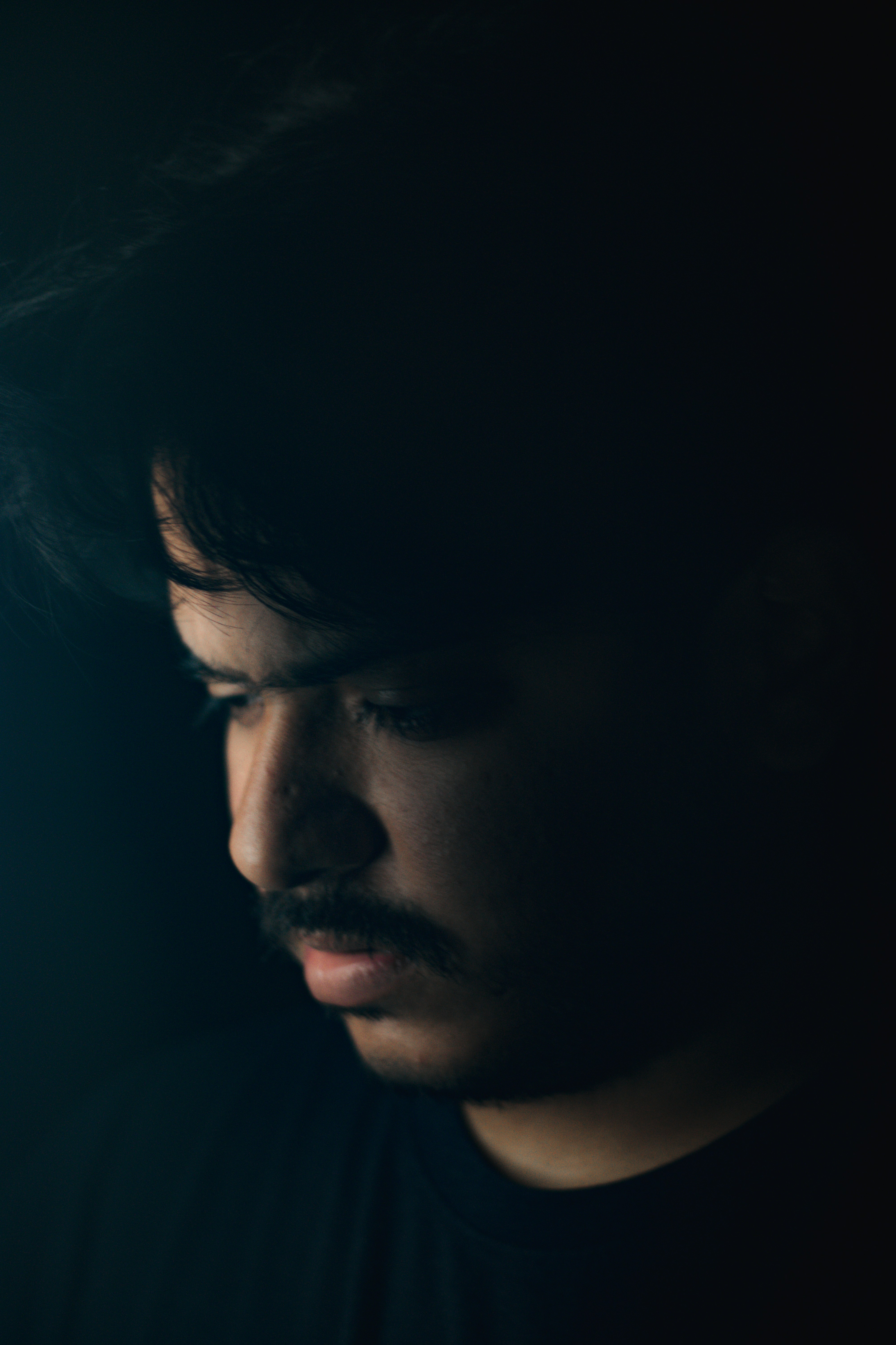 a man in a dark room looking at his cell phone