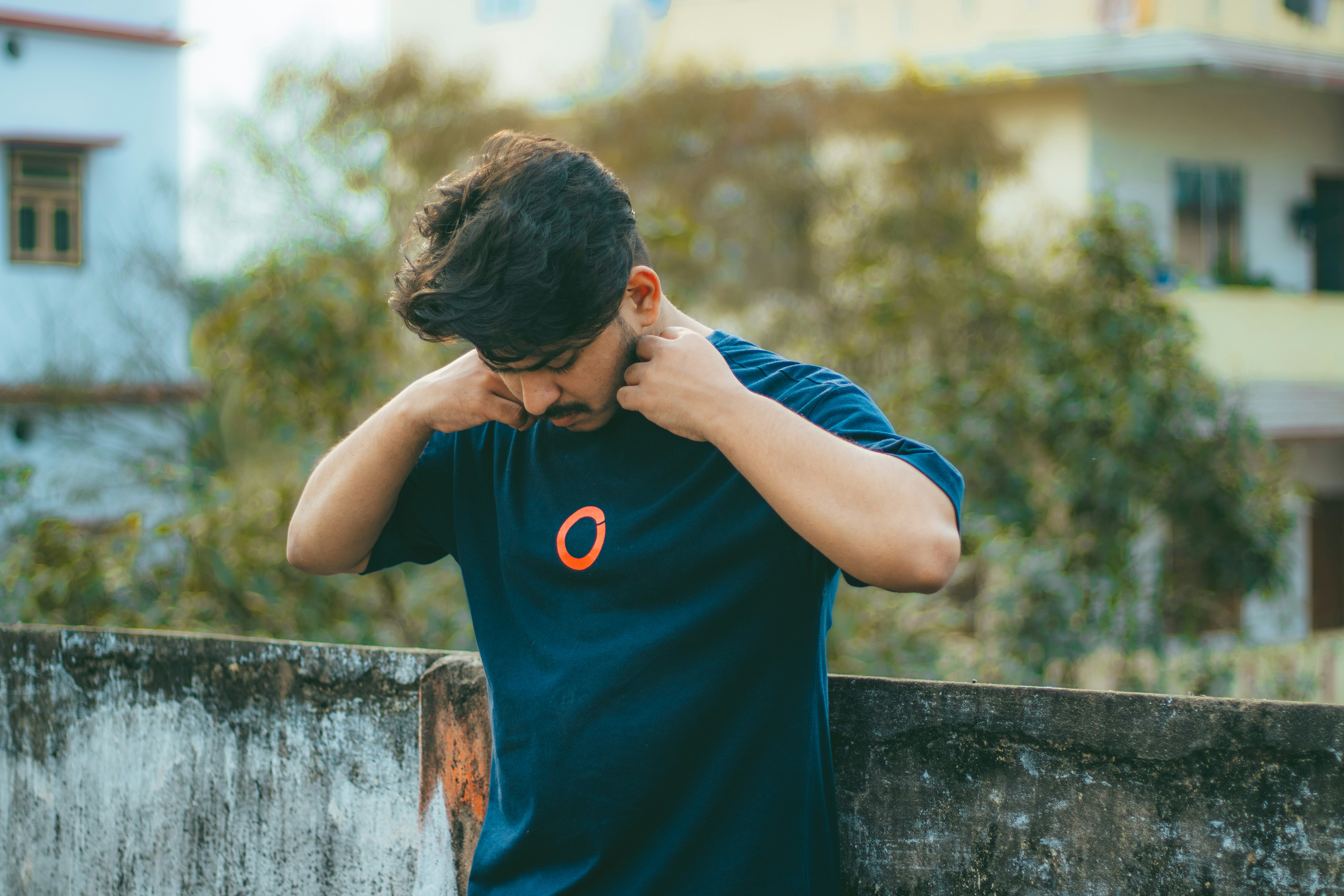 a man is leaning against a wall with his hands on his head