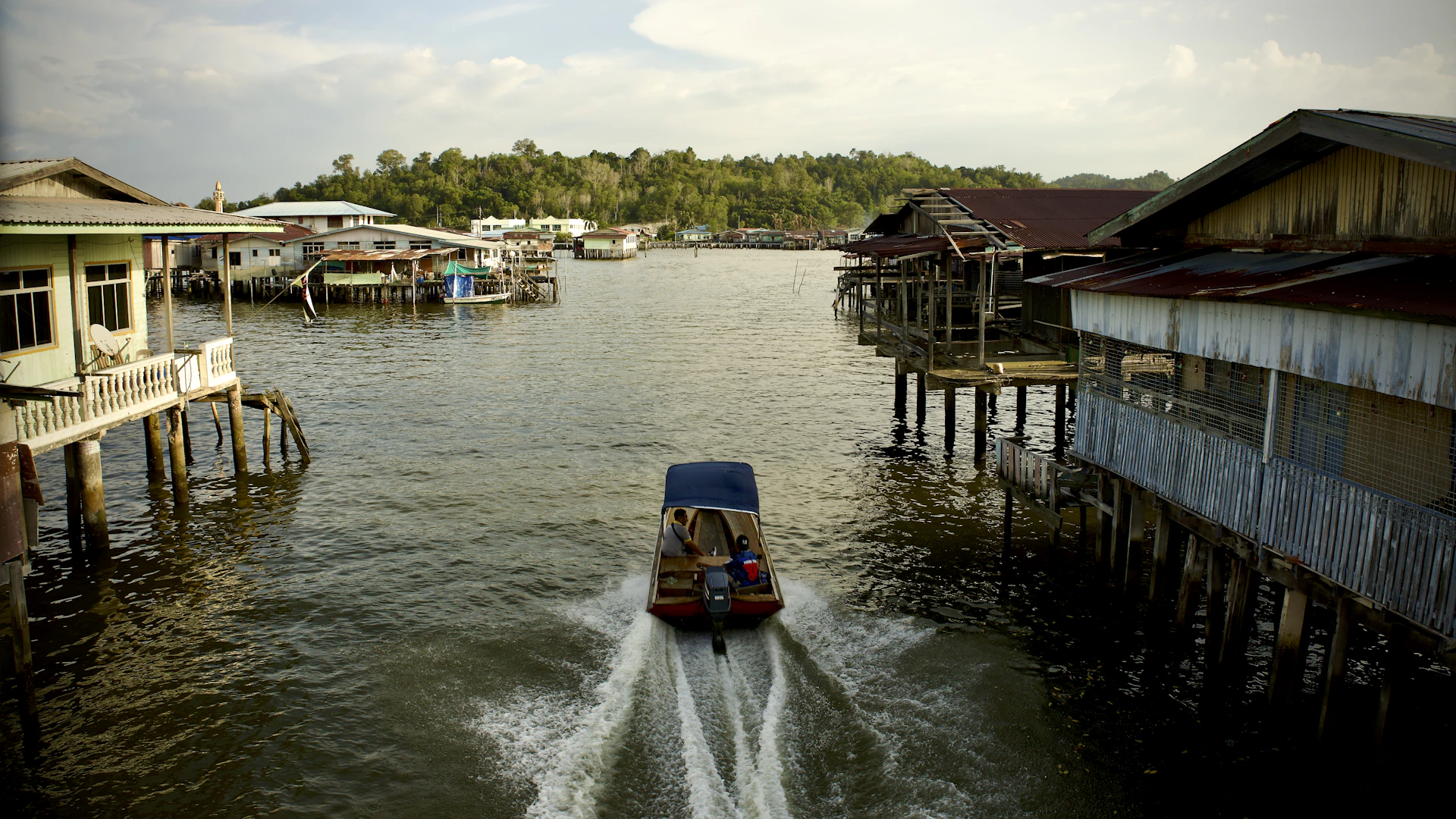 a boat traveling down a river next to a wooden pier