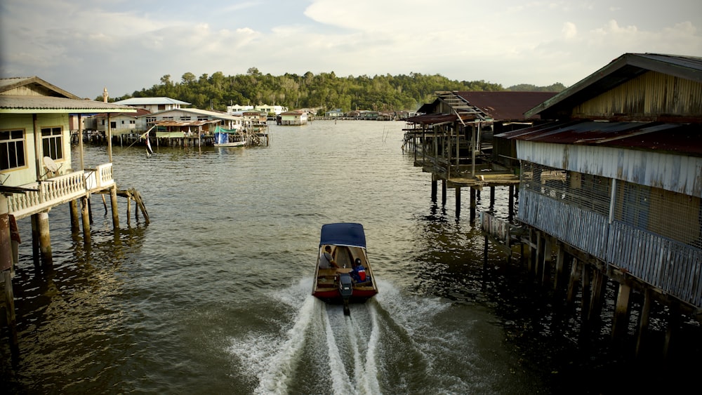 a boat traveling down a river next to a wooden pier