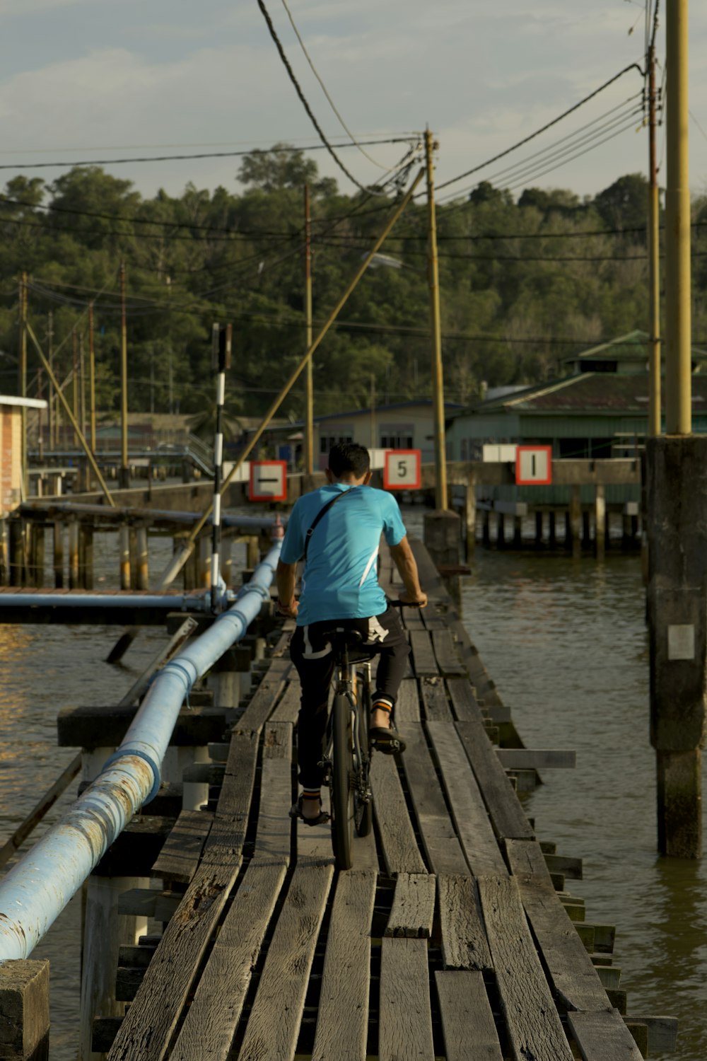 a man riding a bike across a wooden bridge