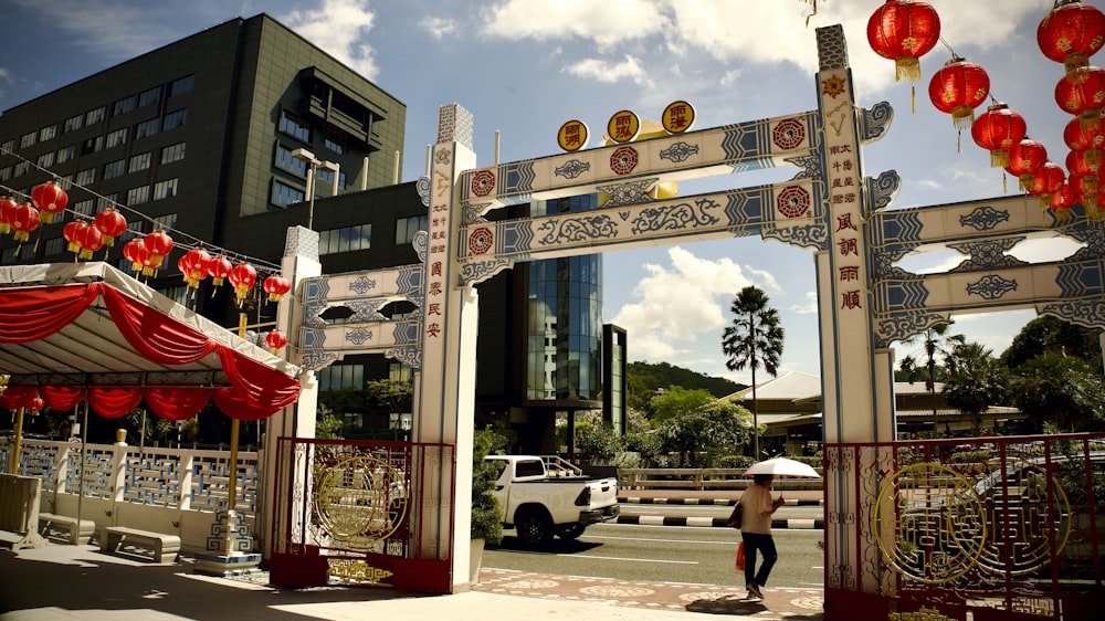 a person with an umbrella walking under a chinese arch