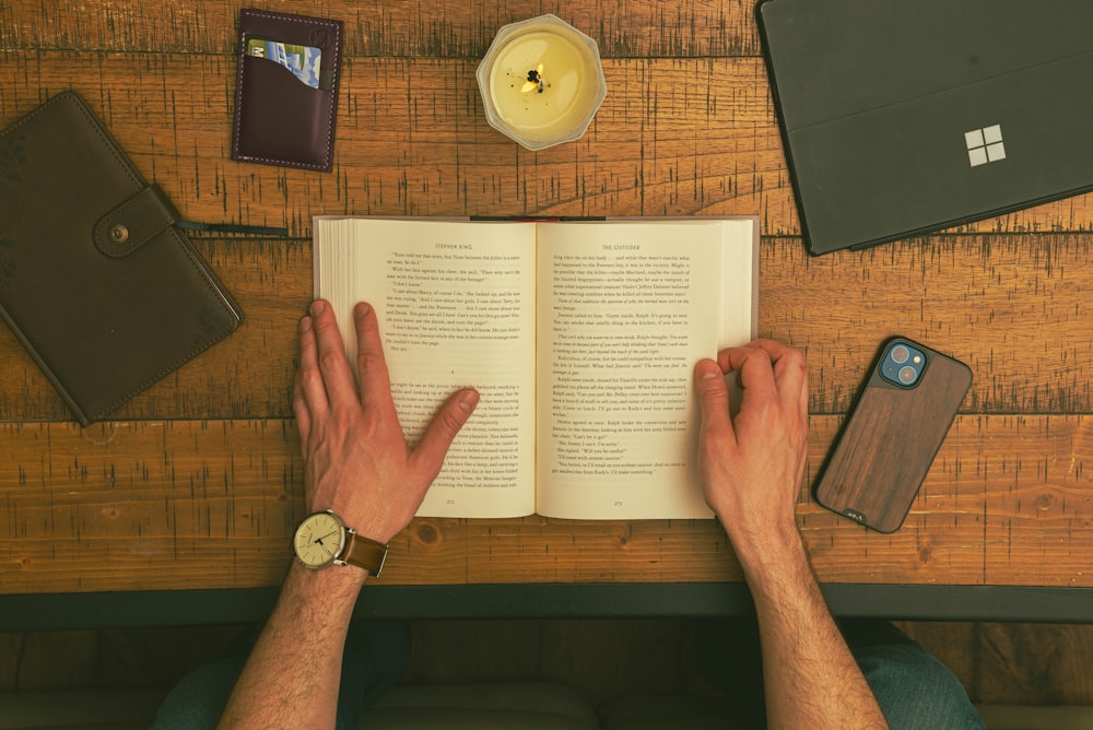 a person reading a book on a wooden table