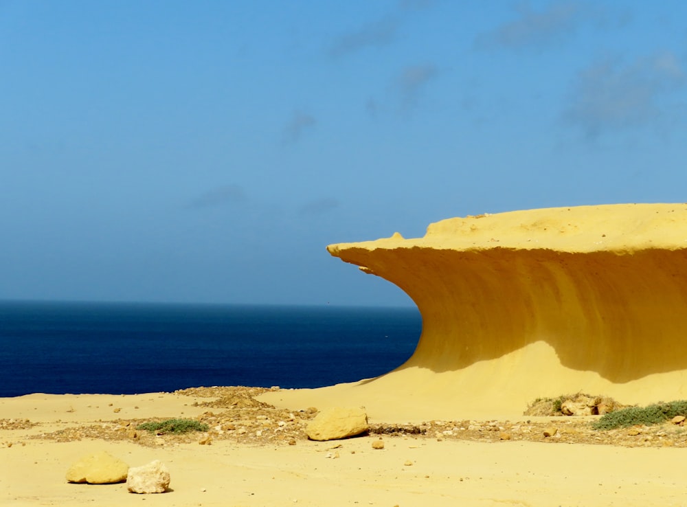 a large rock formation in the sand near the ocean