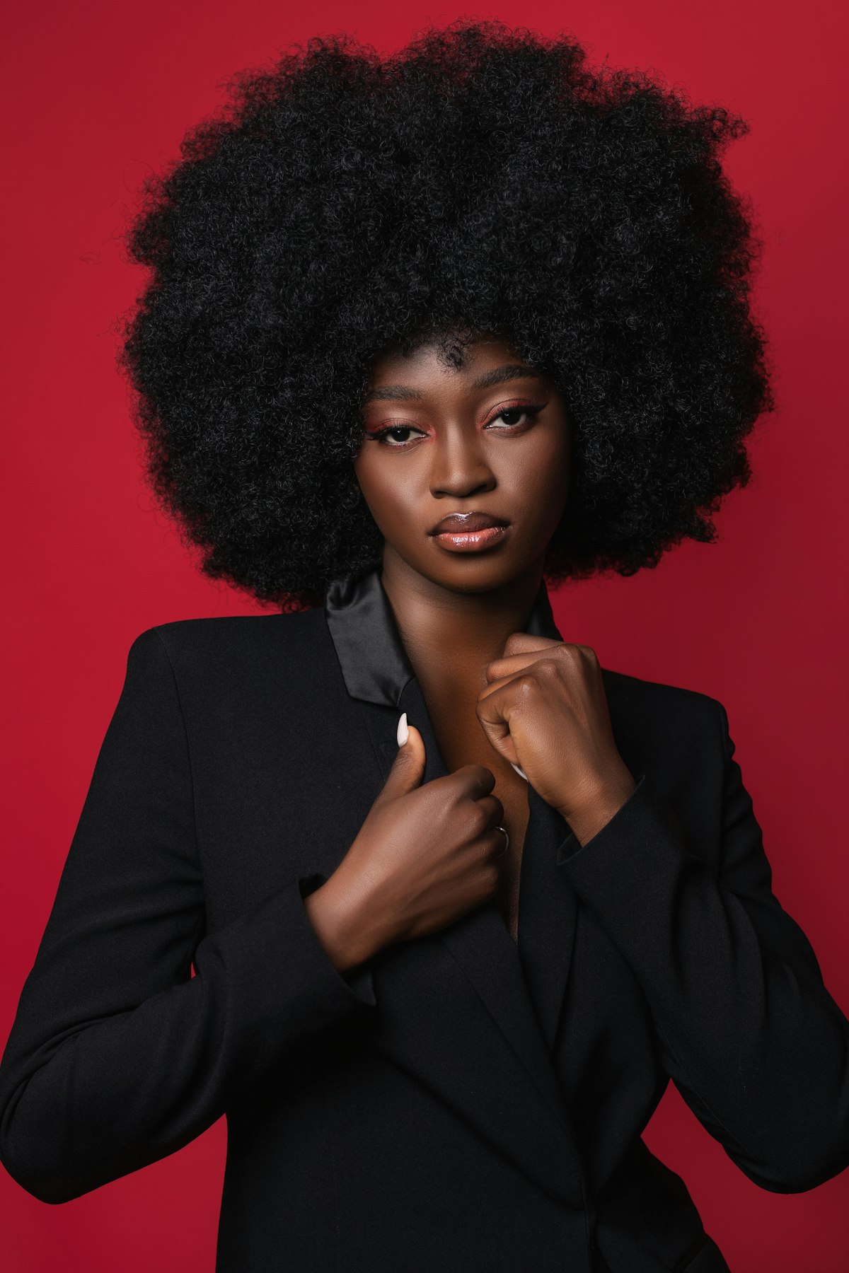 A woman in a black blazer against a red studio wall