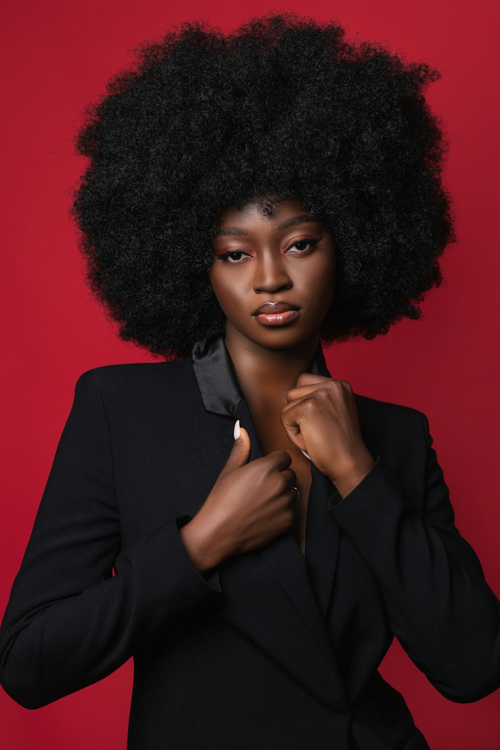 a woman with an afro standing in front of a red background