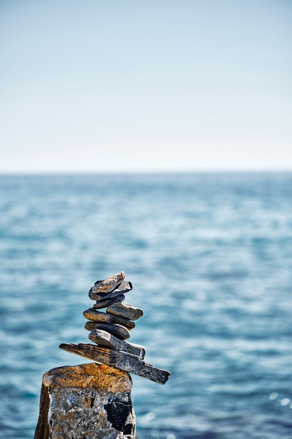 a stack of rocks sitting on top of a rock near the ocean