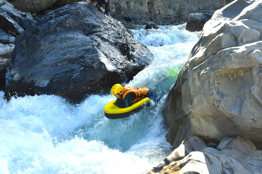 a man riding a yellow raft down a river