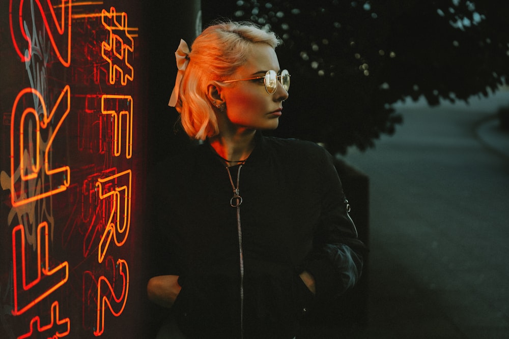 a woman standing next to a neon sign