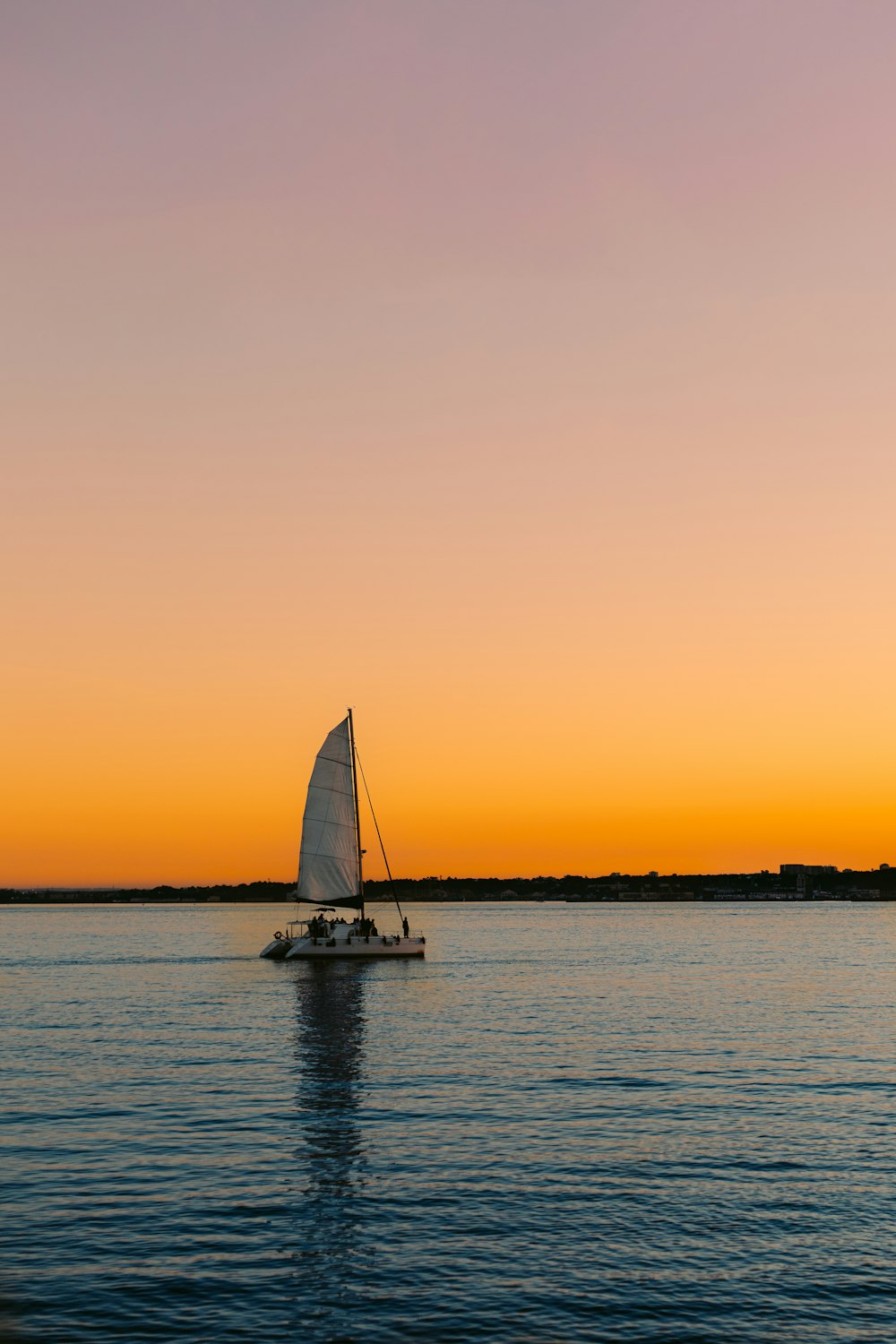 a sailboat in a body of water at sunset