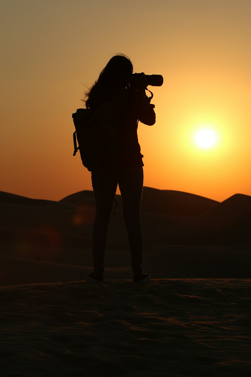 a woman standing in the desert with a camera