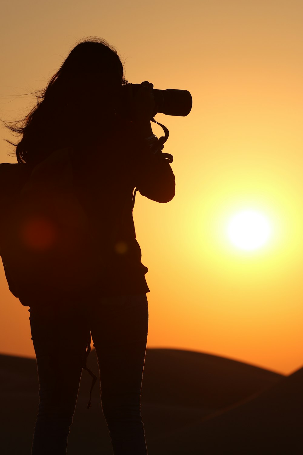 a woman with a camera taking a picture of the sun