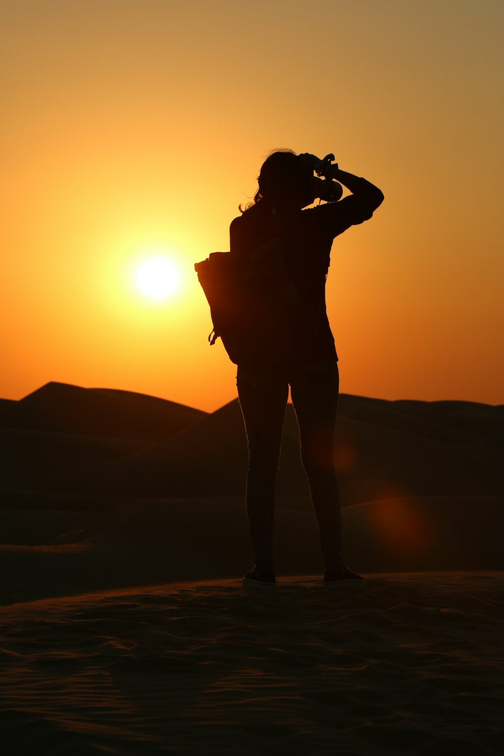 a woman standing in the desert at sunset